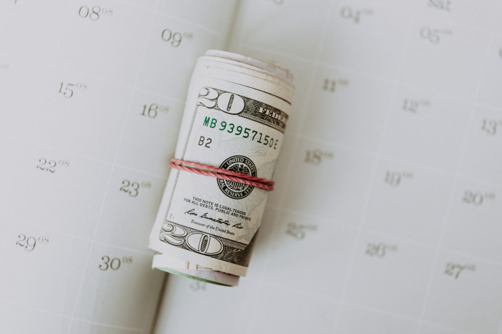 roll of 20 dollar bills sitting on a journal