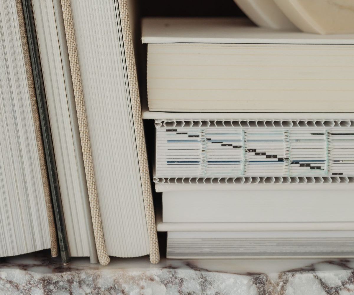 Stacks of white books on a marble shelf.