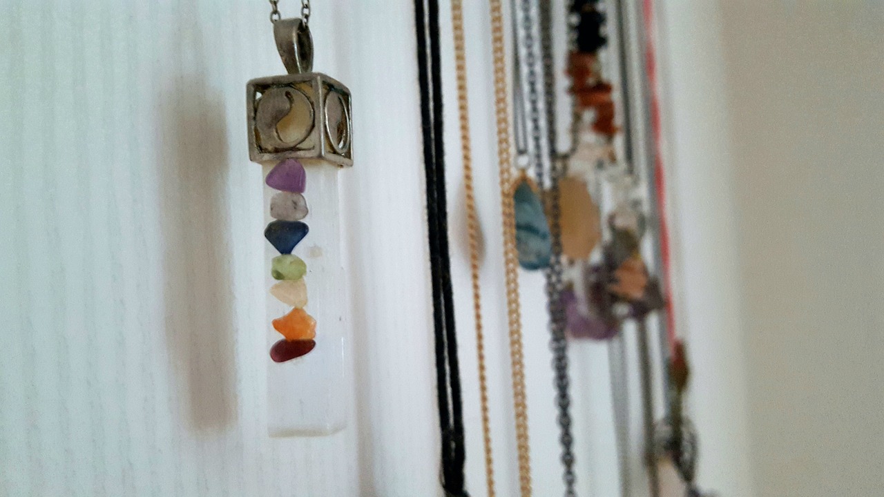 Necklace hanging on the wall with colored chakra stones.