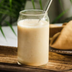 Banana peach smoothie on a wood tray.