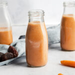 3 banana carrot smoothies on a grey surface.