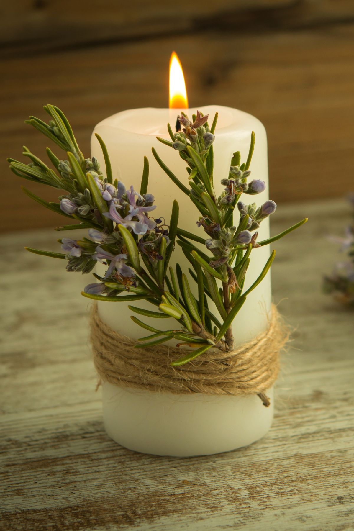 A white candle with herbs and twine wrapped around it.