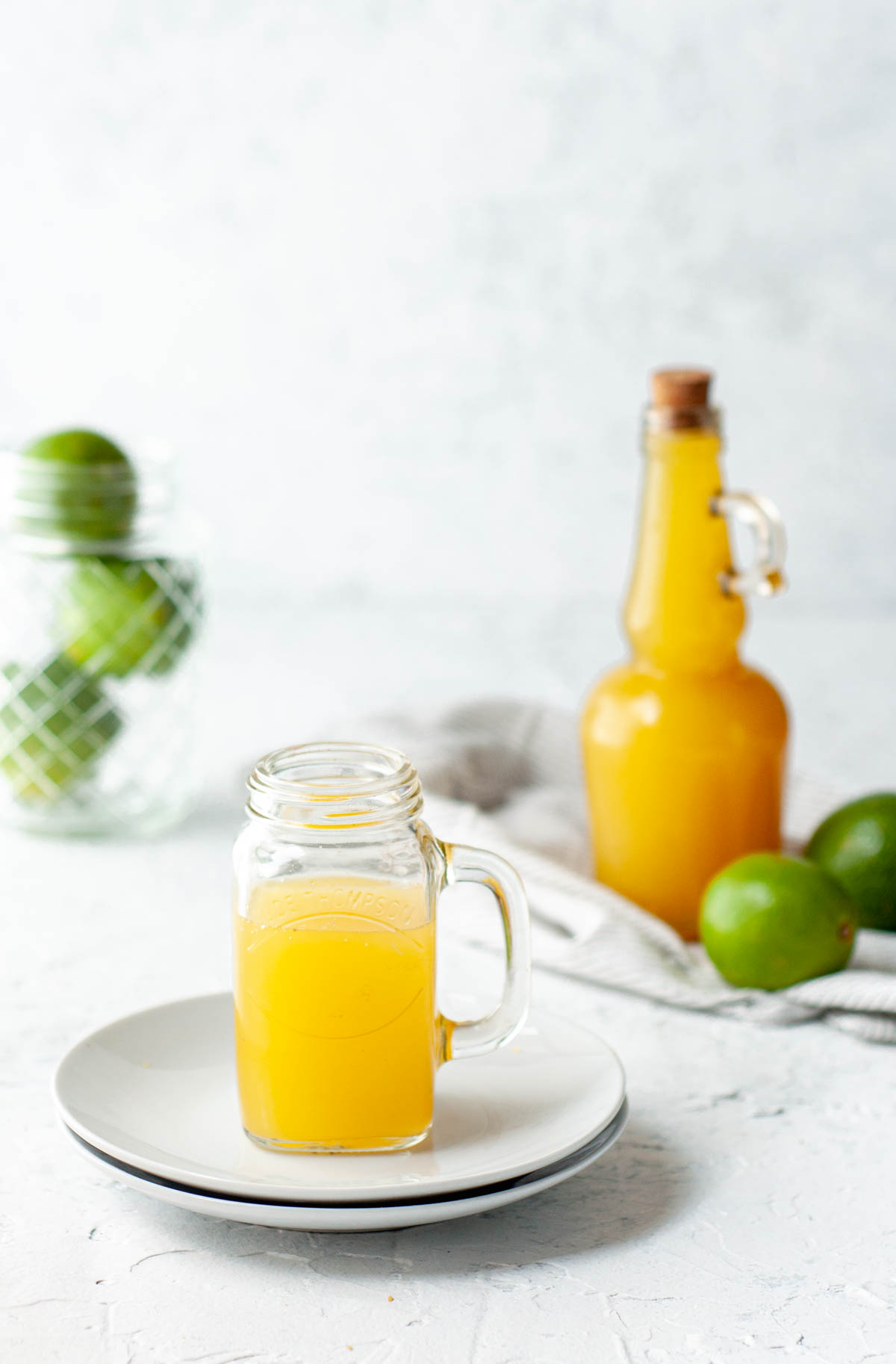 Pineapple Apple Cider Vinegar Shot on white surface with bottle behind it.