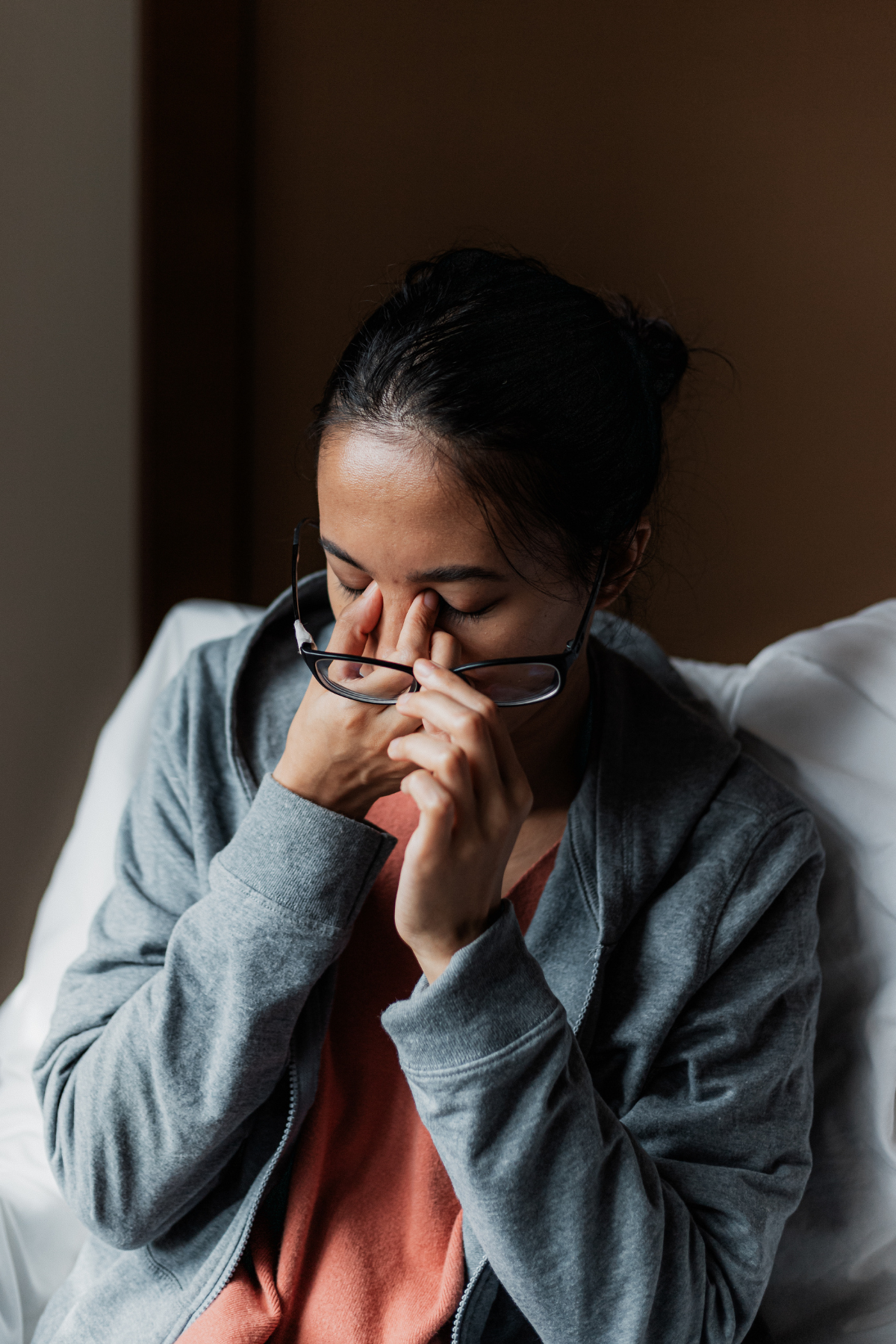 A woman rubbing her eyes looking stressed and anxious.
