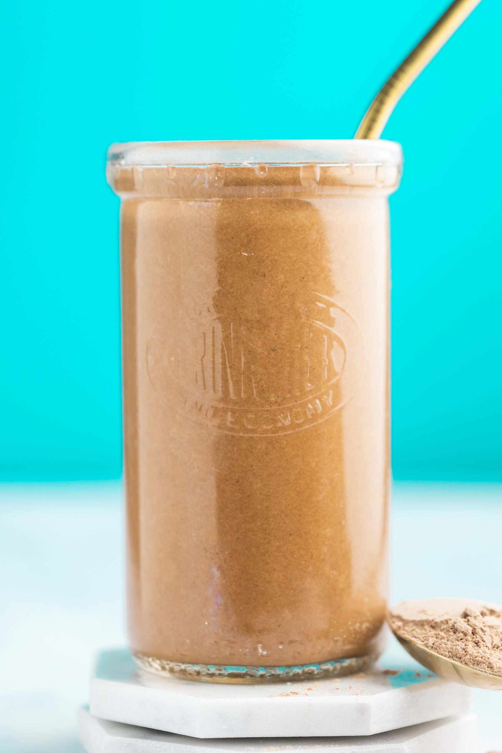 Chocolate protein smoothie on white coasters with blue background.