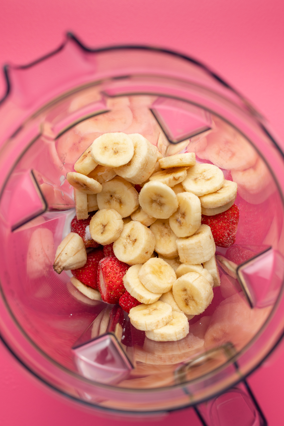 Ingredients for strawberry banana smoothie bowl in blender.