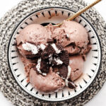Overhead view of scoops of chocolate mint healthy creami ninja ice cream in a black and white bowl on a black and white trivet. Topped with oreo cookies.