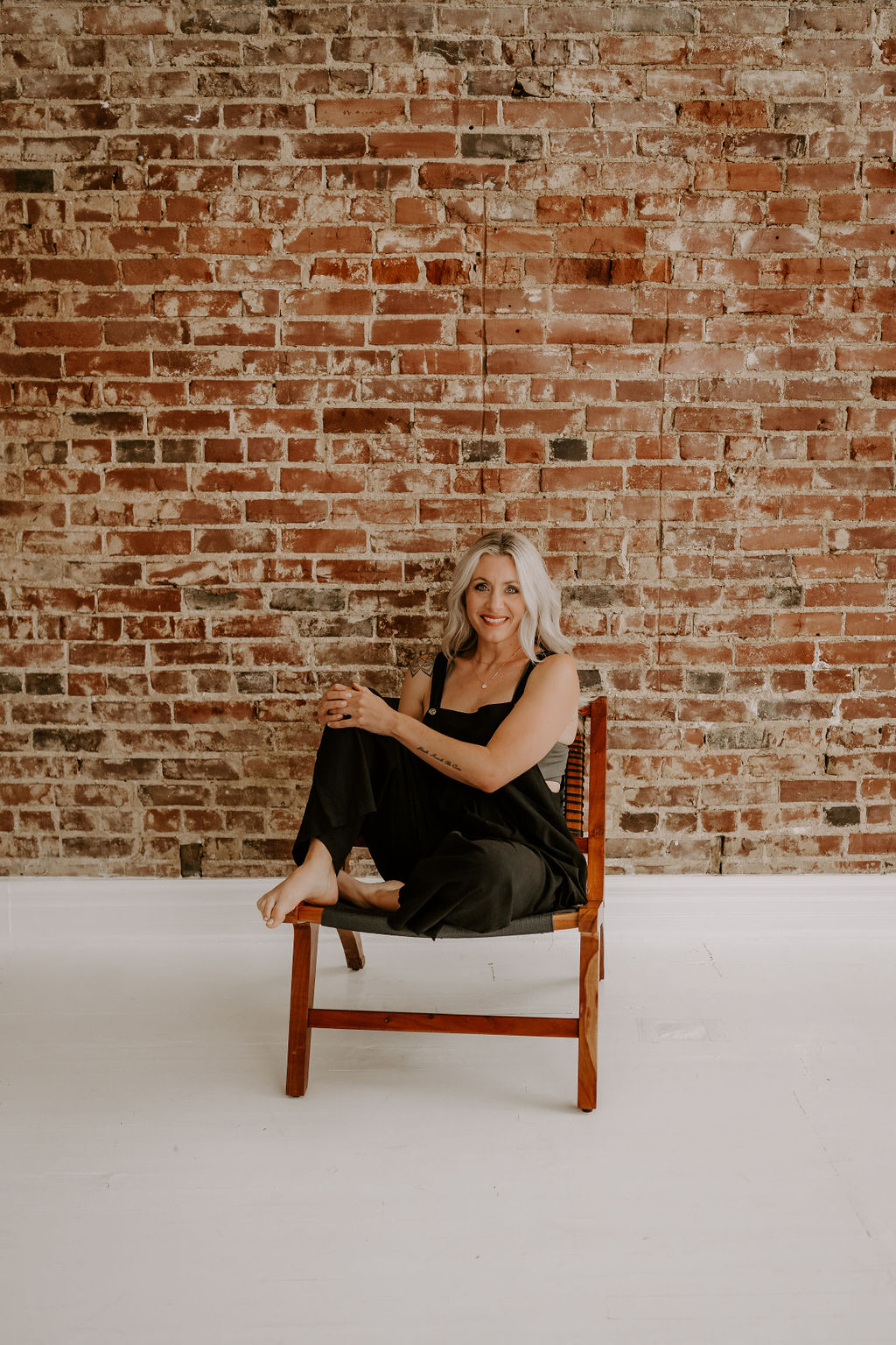 Loren Runion sitting in a chair in front of a brick wall.